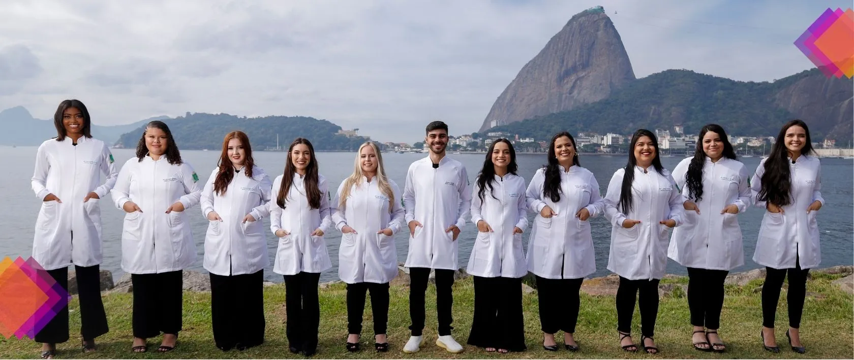 Turma de formandos de jaleco branco reunida em um ensaio fotográfico no aterro do flamengo com o Pão de Açúcar ao fundo, no Rio de Janeiro